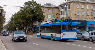A blue and white trolleybus driving on a street in Balti, Moldova.