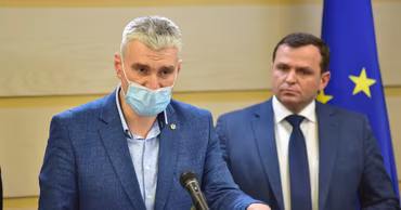 Alexandru Slusari speaking at a podium with another official in the background.