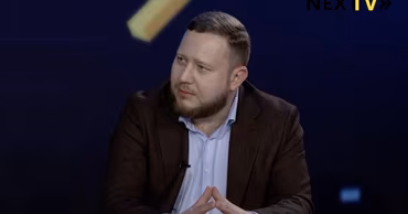Evgheni Buzatu sitting at a table during a television interview.