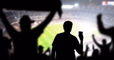 Silhouettes of football fans cheering in a stadium.
