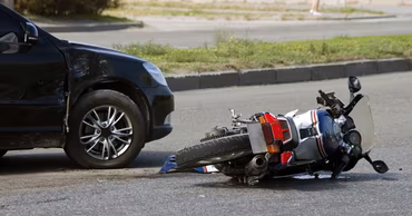 A motorcycle lying on the road next to a car after a traffic accident.
