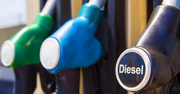 Close-up of fuel pump nozzles at a gas station, highlighting a diesel pump.