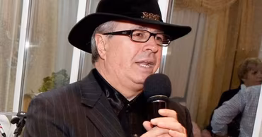 Moldovan singer Ion Suruceanu wearing a black hat and holding a microphone.