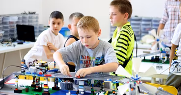 Children working on robotics projects with building blocks in a classroom.