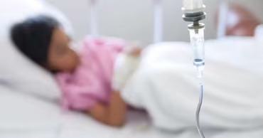 A blurred image of a child lying in a hospital bed with an IV drip.