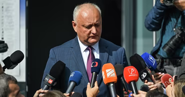 Igor Dodon speaking to a group of journalists holding microphones.