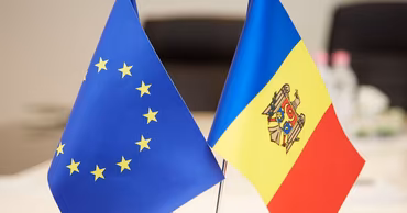 Flags of the European Union and Moldova placed side by side on a table.