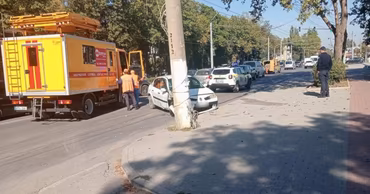A damaged white car at the scene of a traffic accident with police present.