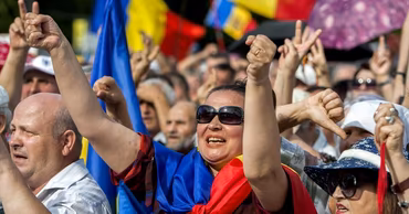 Protesters in Moldova holding flags and gesturing during a public demonstration.