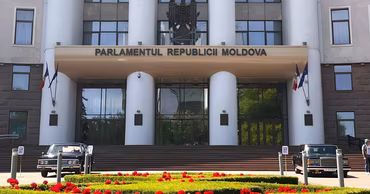 The building of the Parliament of the Republic of Moldova with cars parked in front.