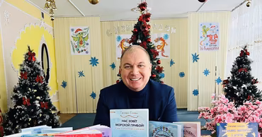Grigore Gacichevici sitting at a table with children's books in a decorated room.