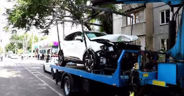 A heavily damaged white car being loaded onto a tow truck after an accident.