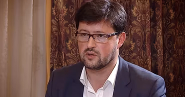 A portrait of Ion Onța wearing glasses and a suit jacket.
