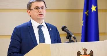 Igor Grosu speaking at a podium with Moldovan and EU flags in the background.