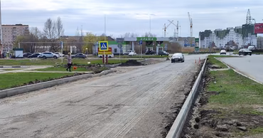 A road under construction with curbs and surrounding infrastructure in a suburban area.