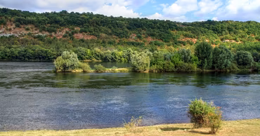 A scenic view of the Dniester River with green trees and hills in the background.