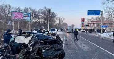 A severely damaged car at a crash site on a highway with police officers present.