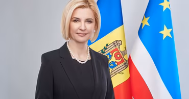Irina Vlah standing in front of the Moldovan and Gagauzian flags.