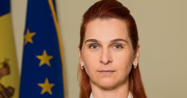 Portrait of Ana Revenco with Moldovan and European Union flags in the background.