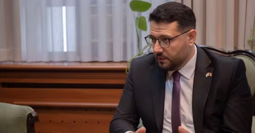 Alexandru Trubca sitting in a chair and speaking.