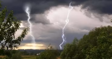 Lightning strikes during a thunderstorm over a rural landscape.
