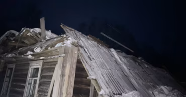 A damaged wooden house roof with missing slate sheets after a storm at night.