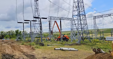 Workers repairing high-voltage power lines and electrical infrastructure in a field.