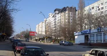 A street view of Burebista street in the Botanica district of Chisinau with residential buildings and cars.