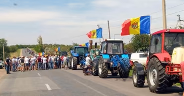 Moldovan farmers protesting on a road with tractors and Moldovan flags.