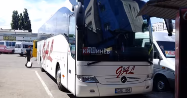 A white passenger bus parked at a station in Chisinau with a sign indicating the destination.