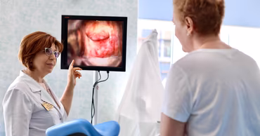 A doctor explaining a colposcopy result to a patient in a medical office.