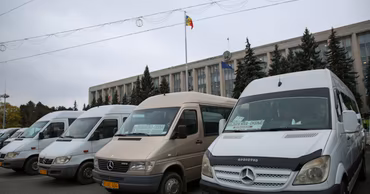 Several passenger transport vans parked in front of a government building in Moldova.