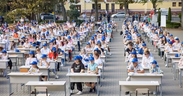 Many people sitting at desks in a public square in Chisinau participating in a dictation event.