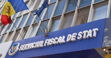 The building facade of the State Tax Service of Moldova with its sign and flags.