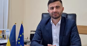 Dumitru Vartic sitting at a desk with Moldovan and European Union flags.