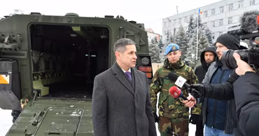 Moldovan Minister of Defense Anatolie Nosatii giving an interview in front of military equipment.