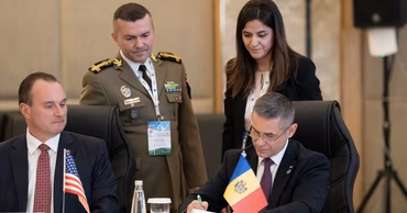 Anatolie Nosatii, Minister of Defense of Moldova, signing a document at an official meeting.