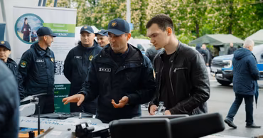 Moldovan border police officers demonstrating drone technology to a civilian.