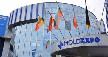 The exterior of the Moldexpo exhibition center building in Chisinau with flags flying.