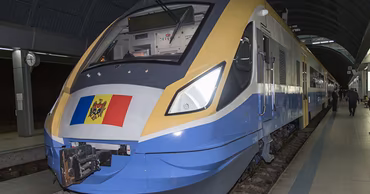 A modern passenger train with the Moldovan flag at a railway station.