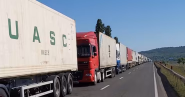 A long line of heavy freight trucks driving on a highway.