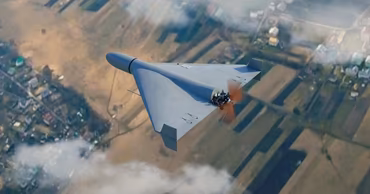 A Shahed-type kamikaze drone flying over a rural landscape.