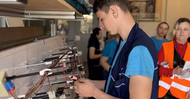 A young man working on an assembly line in a factory setting.