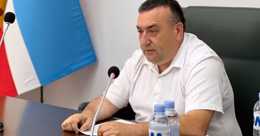 Valentin Gaidarzhi sitting at a table with a microphone in front of him.