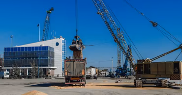 Industrial cranes loading grain into trucks at a port facility in Moldova.