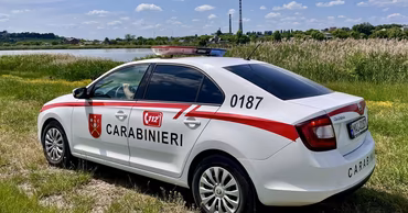 A white patrol car of the Moldovan Carabinieri parked in a grassy area.