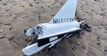 Debris of a drone or missile lying on a sandy beach.