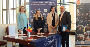 Representatives of the National Trade Union Confederation of Moldova standing at a table with organization branding.