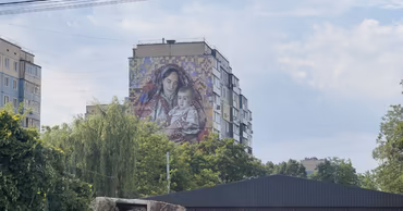 A large mural on a residential building in Buiucani depicting a mother and child.
