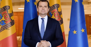 Official portrait of Vasile Tofan standing in front of Moldovan and European Union flags.